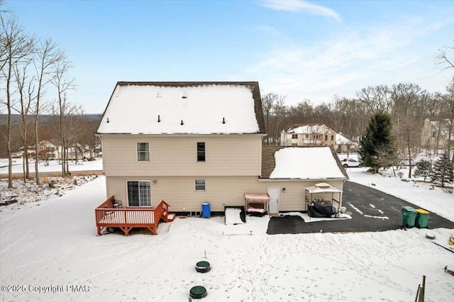 snow covered back of property featuring a deck