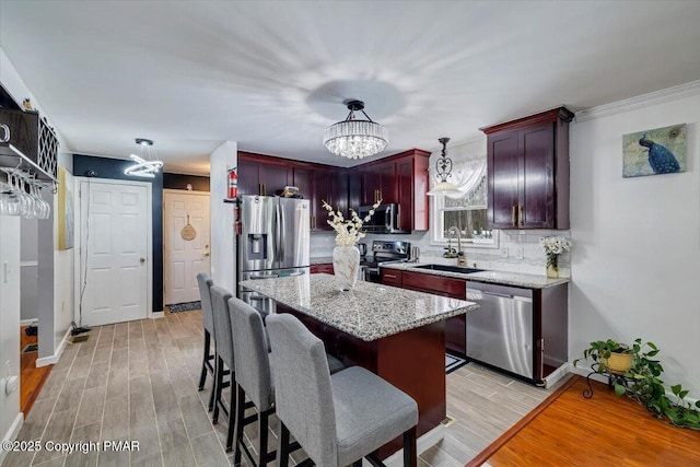 kitchen with decorative light fixtures, sink, a center island, light stone counters, and stainless steel appliances