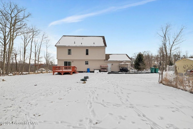 snow covered back of property featuring a wooden deck