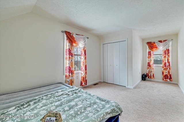 carpeted bedroom with visible vents, a closet, baseboards, and a textured ceiling