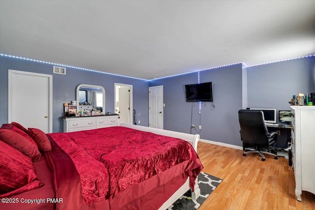 bedroom featuring light wood-style floors, visible vents, and baseboards