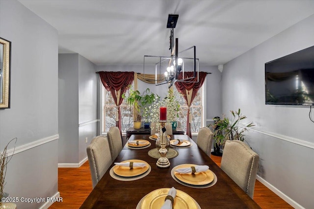 dining area featuring an inviting chandelier, baseboards, and wood finished floors