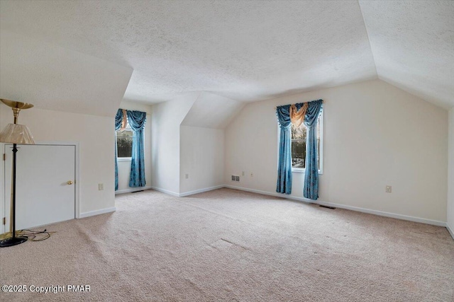 additional living space featuring baseboards, visible vents, carpet, vaulted ceiling, and a textured ceiling