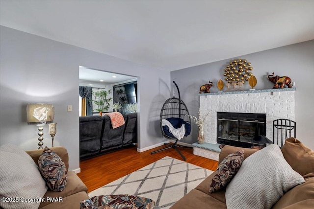 living area with a brick fireplace, wood finished floors, and baseboards