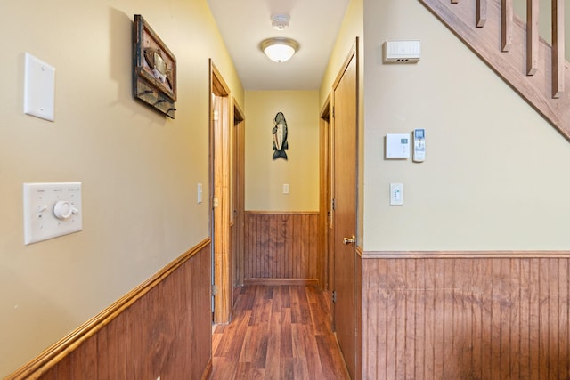 hall with wood walls, wainscoting, and wood finished floors