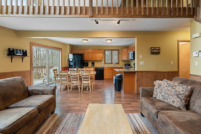 living area featuring a wainscoted wall, wooden walls, and wood finished floors