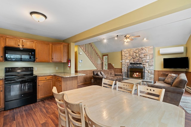 kitchen with a wainscoted wall, lofted ceiling, a wall mounted AC, open floor plan, and black appliances