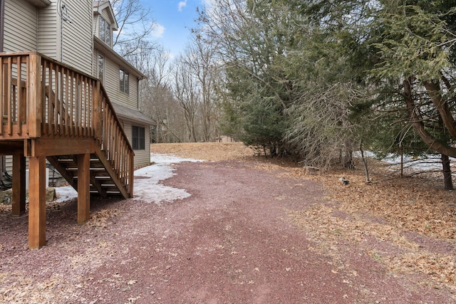 view of yard featuring a deck, driveway, and stairway