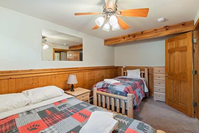 bedroom featuring ceiling fan, carpet floors, wainscoting, and wooden walls