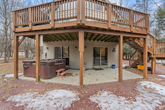 rear view of property with a hot tub, stairway, a wooden deck, and a patio