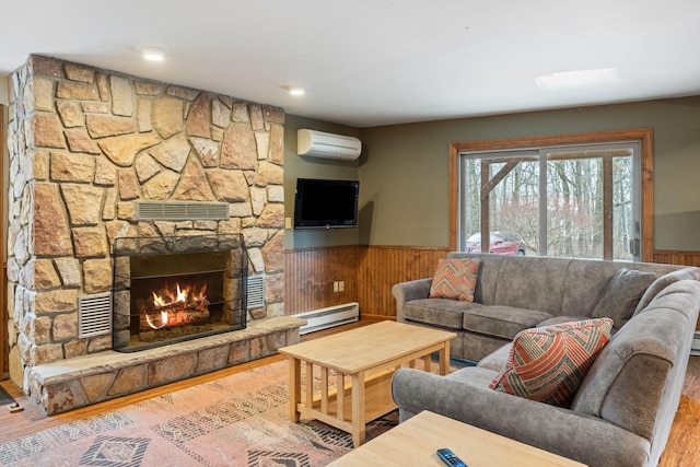 living room with a wainscoted wall, a baseboard radiator, wood finished floors, a fireplace, and a wall mounted AC