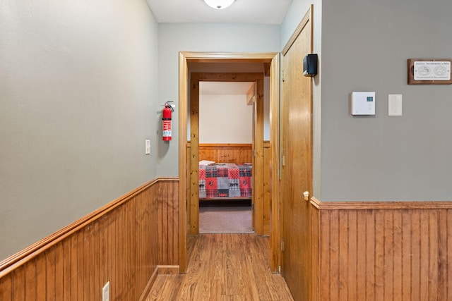 hall with a wainscoted wall, wooden walls, and wood finished floors