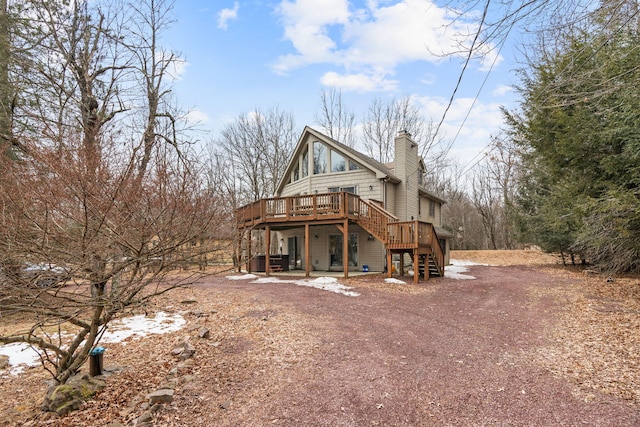 rear view of house featuring stairs, a deck, and a chimney