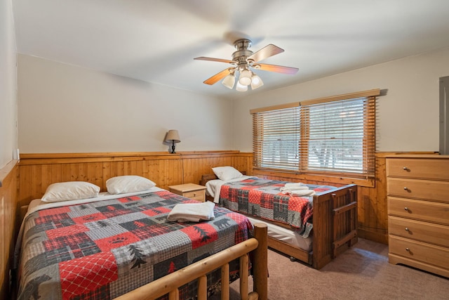 bedroom with a ceiling fan, carpet, a wainscoted wall, and wooden walls