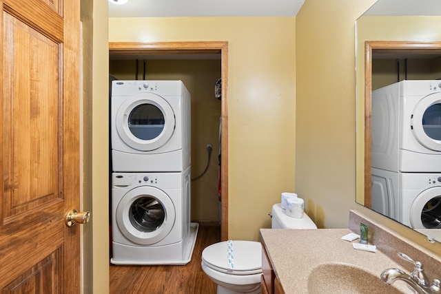 washroom featuring stacked washer / dryer, laundry area, a sink, and wood finished floors