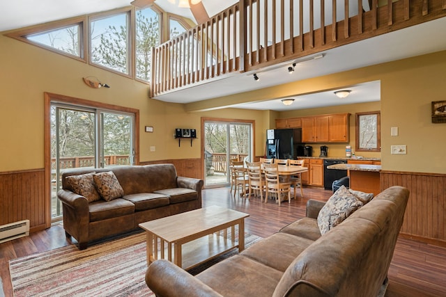 living room featuring dark wood finished floors, wainscoting, and wood walls