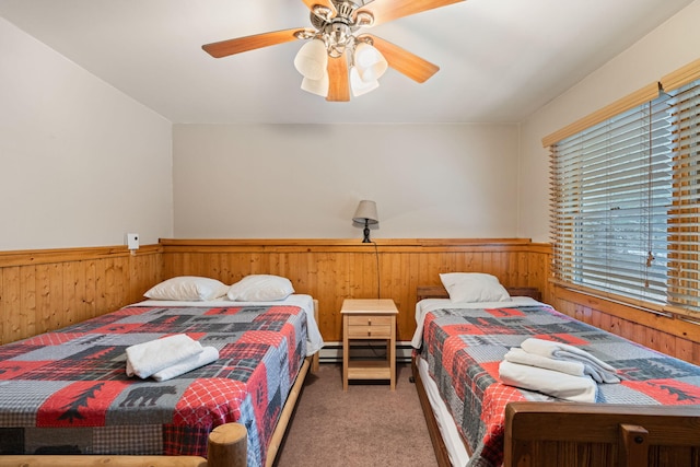 bedroom with a wainscoted wall, ceiling fan, carpet flooring, and wooden walls