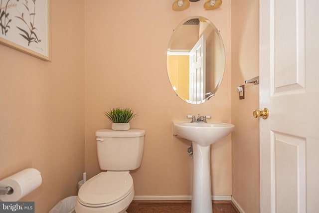 bathroom with a sink, toilet, and baseboards