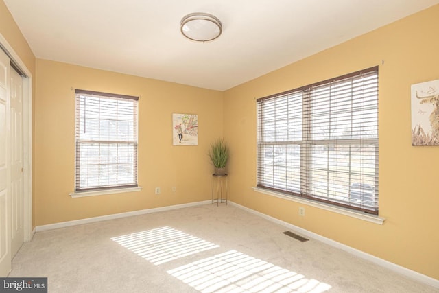 carpeted empty room featuring visible vents and baseboards