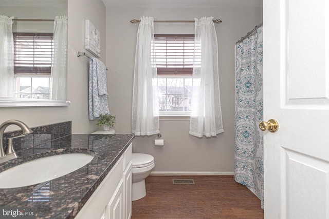 full bathroom featuring toilet, wood finished floors, vanity, visible vents, and baseboards