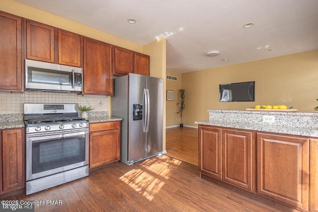 kitchen featuring appliances with stainless steel finishes, visible vents, dark wood finished floors, and backsplash