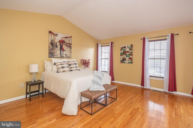 bedroom featuring lofted ceiling, baseboards, and light wood-style floors