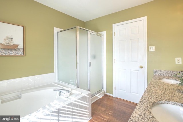 bathroom featuring a garden tub, a sink, a shower stall, and wood finished floors