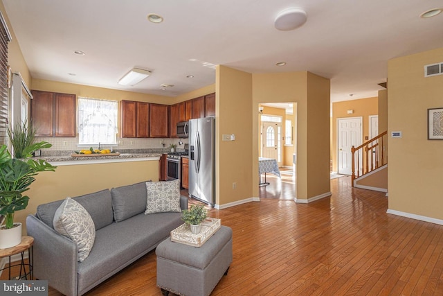 living room with baseboards, visible vents, stairway, light wood-style floors, and recessed lighting