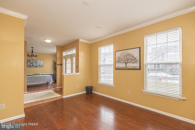 empty room with ornamental molding, baseboards, and wood finished floors