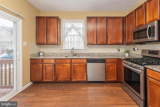 kitchen featuring dark wood-style floors, appliances with stainless steel finishes, a sink, and decorative backsplash