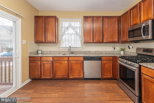 kitchen with light stone counters, dark wood-style flooring, tasteful backsplash, appliances with stainless steel finishes, and a sink