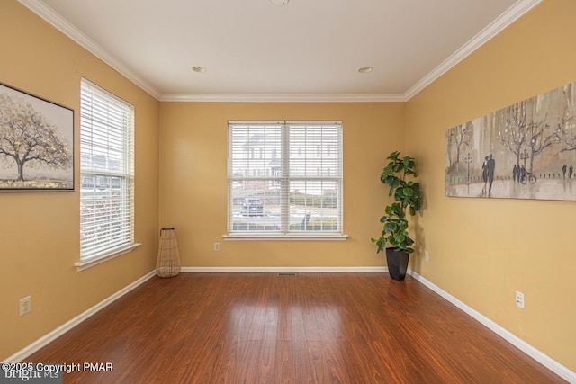 empty room featuring crown molding, wood finished floors, and baseboards