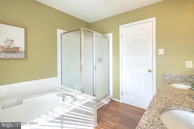 bathroom featuring a garden tub, wood finished floors, a sink, and a shower stall