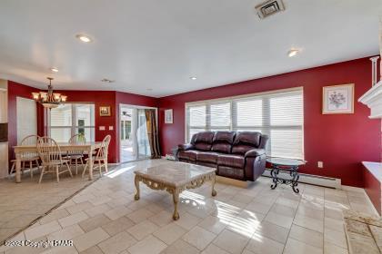 living room with visible vents, baseboard heating, and a chandelier