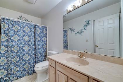 bathroom with toilet, tile patterned floors, curtained shower, and vanity