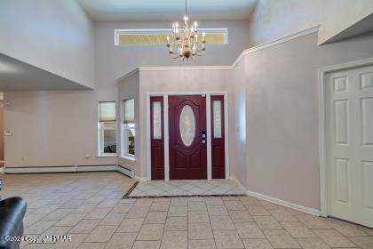 foyer entrance featuring plenty of natural light, a baseboard radiator, baseboards, and an inviting chandelier