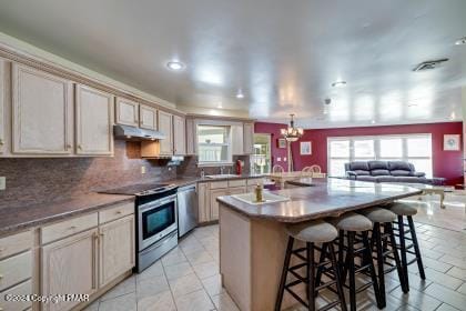 kitchen with a breakfast bar area, decorative backsplash, appliances with stainless steel finishes, open floor plan, and under cabinet range hood