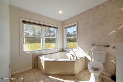 full bath with baseboards, a garden tub, toilet, and tile patterned floors