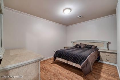 bedroom featuring ornamental molding, visible vents, and wood finished floors