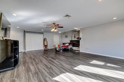 living area featuring baseboards, visible vents, a ceiling fan, wood finished floors, and recessed lighting