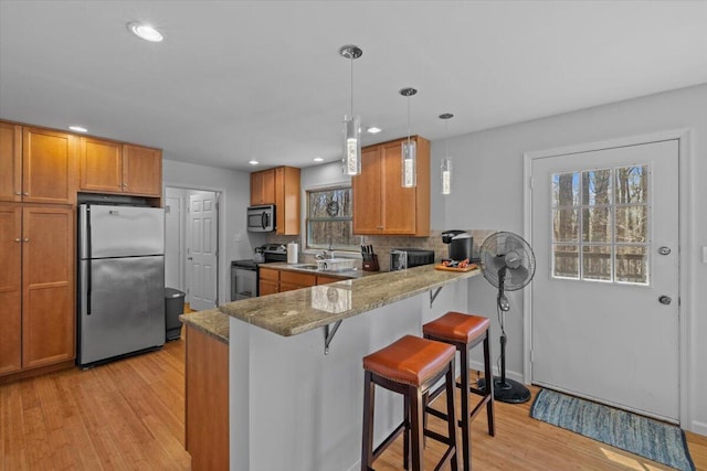 1232 Redwood Ter, Pocono Pines, PA 18350 - kitchen with light wood finished floors, appliances with stainless steel finishes, brown cabinets, and a kitchen breakfast bar