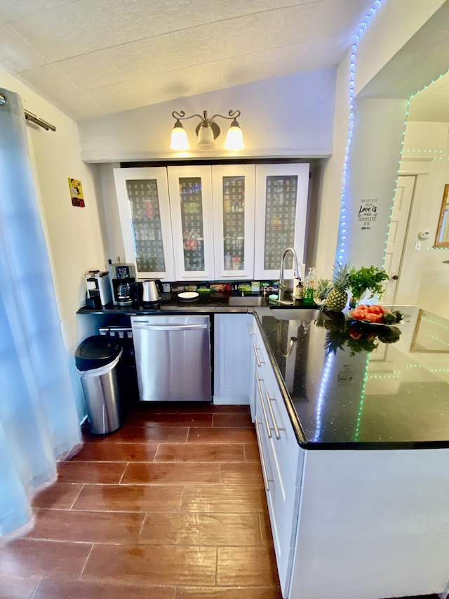 kitchen with white cabinetry, wood finish floors, a sink, glass insert cabinets, and stainless steel dishwasher