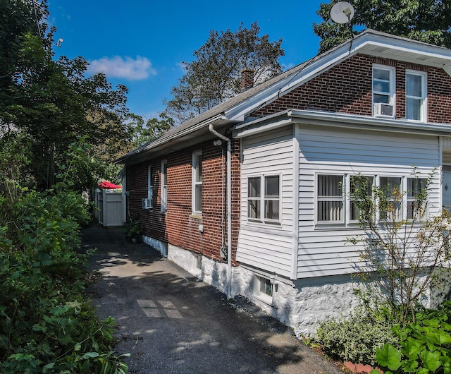 view of property exterior with cooling unit, brick siding, and a chimney