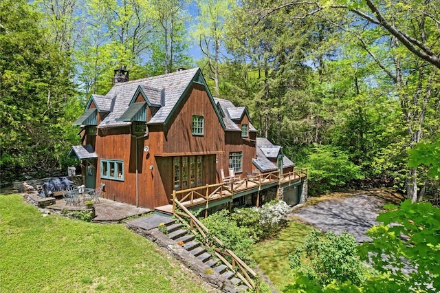 rear view of house featuring french doors, a chimney, a lawn, a wooden deck, and a patio