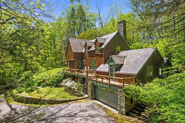 view of front of property featuring a chimney, asphalt driveway, an attached garage, and a deck