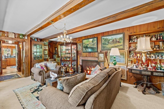 living room with wood walls, light carpet, a chandelier, beam ceiling, and a fireplace