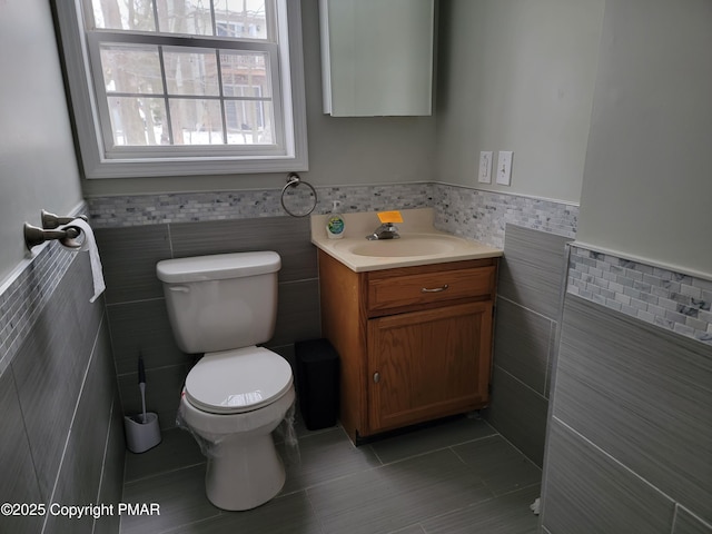 bathroom with vanity, toilet, tile patterned flooring, and tile walls