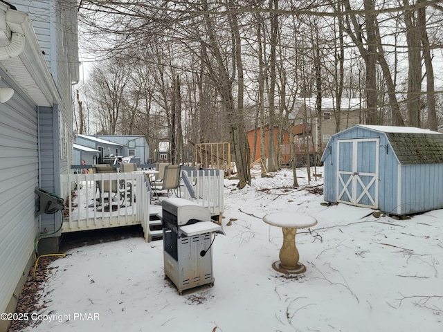 yard covered in snow featuring a storage unit and a deck