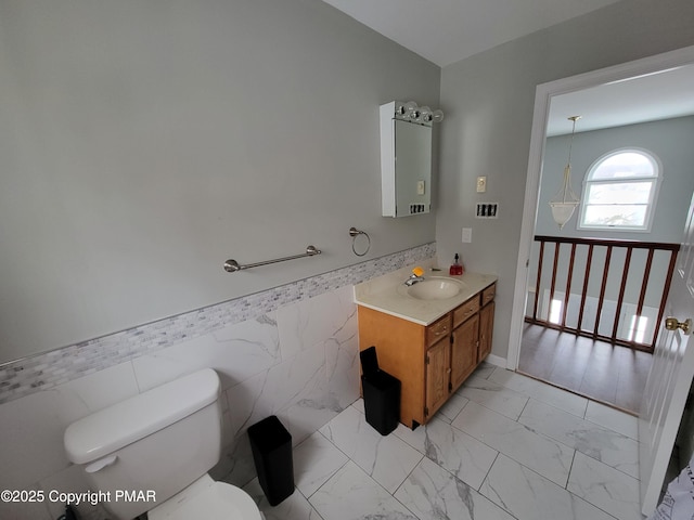 bathroom featuring vanity, tile walls, and toilet