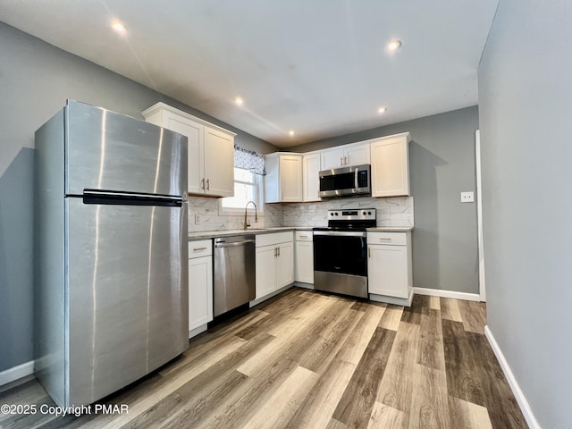 kitchen featuring sink, white cabinetry, tasteful backsplash, light hardwood / wood-style flooring, and stainless steel appliances